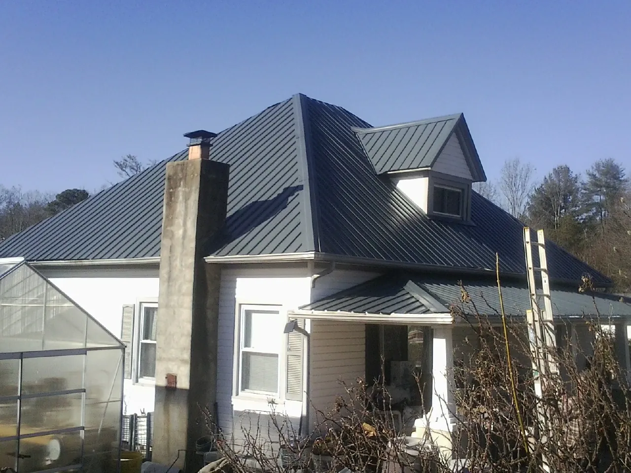 Dark blue standing seam metal roof on a white farmhouse with dormer — Slate & Tile Roof Repair by Roofing Brothers in Sully