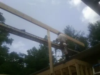 Carpenter setting a ridge beam over a new addition frame — Ice Dam Removal by Roofing Brothers in Sully