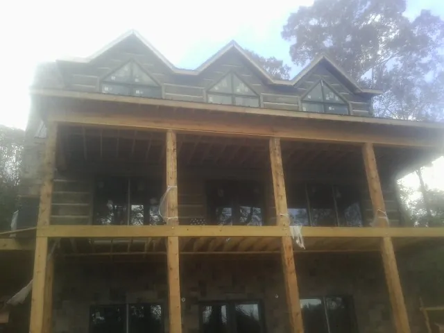 Dormers and porch framing on a large log home under construction — Roof Coating work by our crew in Sully