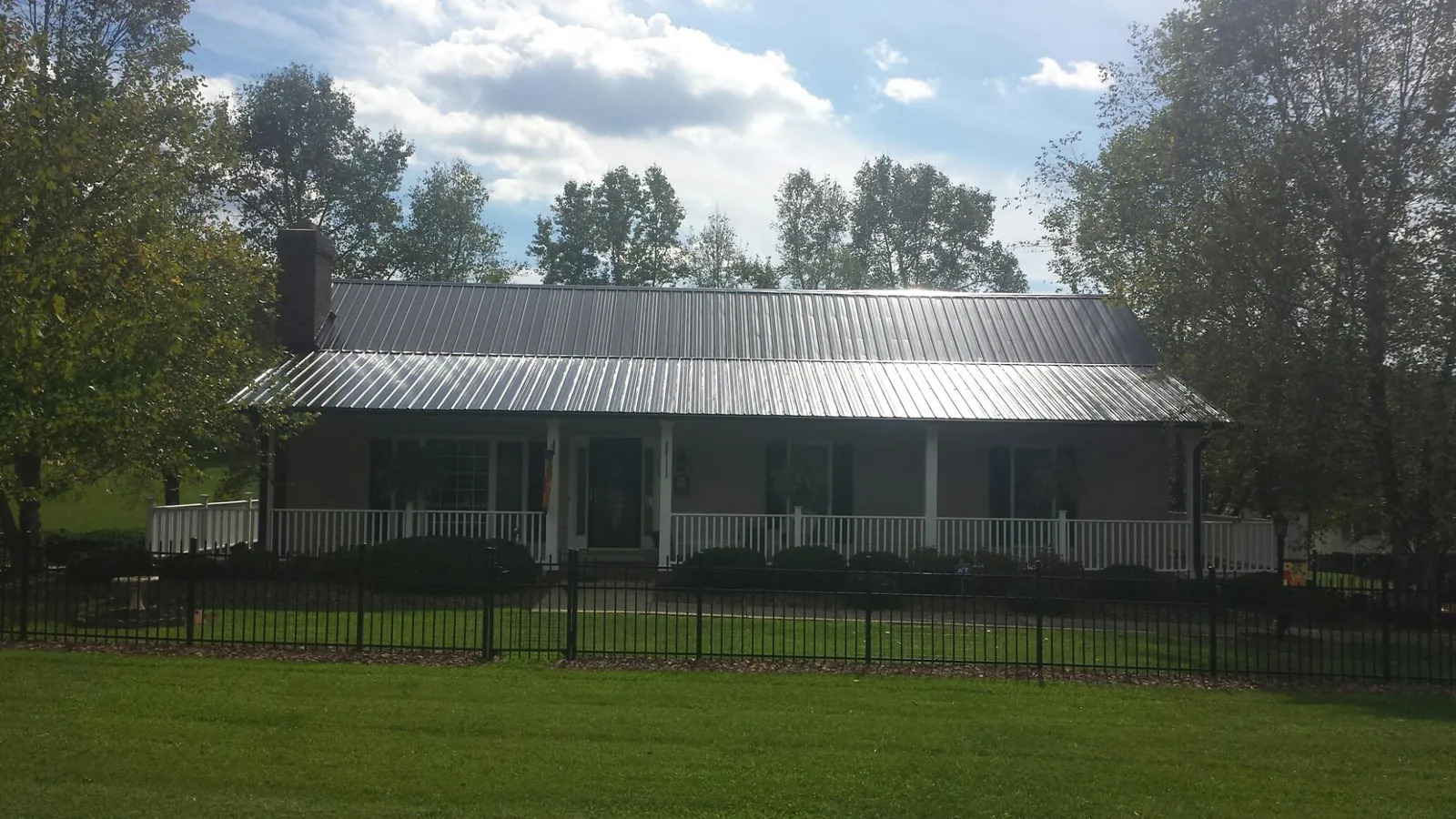 Gray metal roof on a brick ranch with a full width front porch — Gutter Guard Installation work by our crew in Sully
