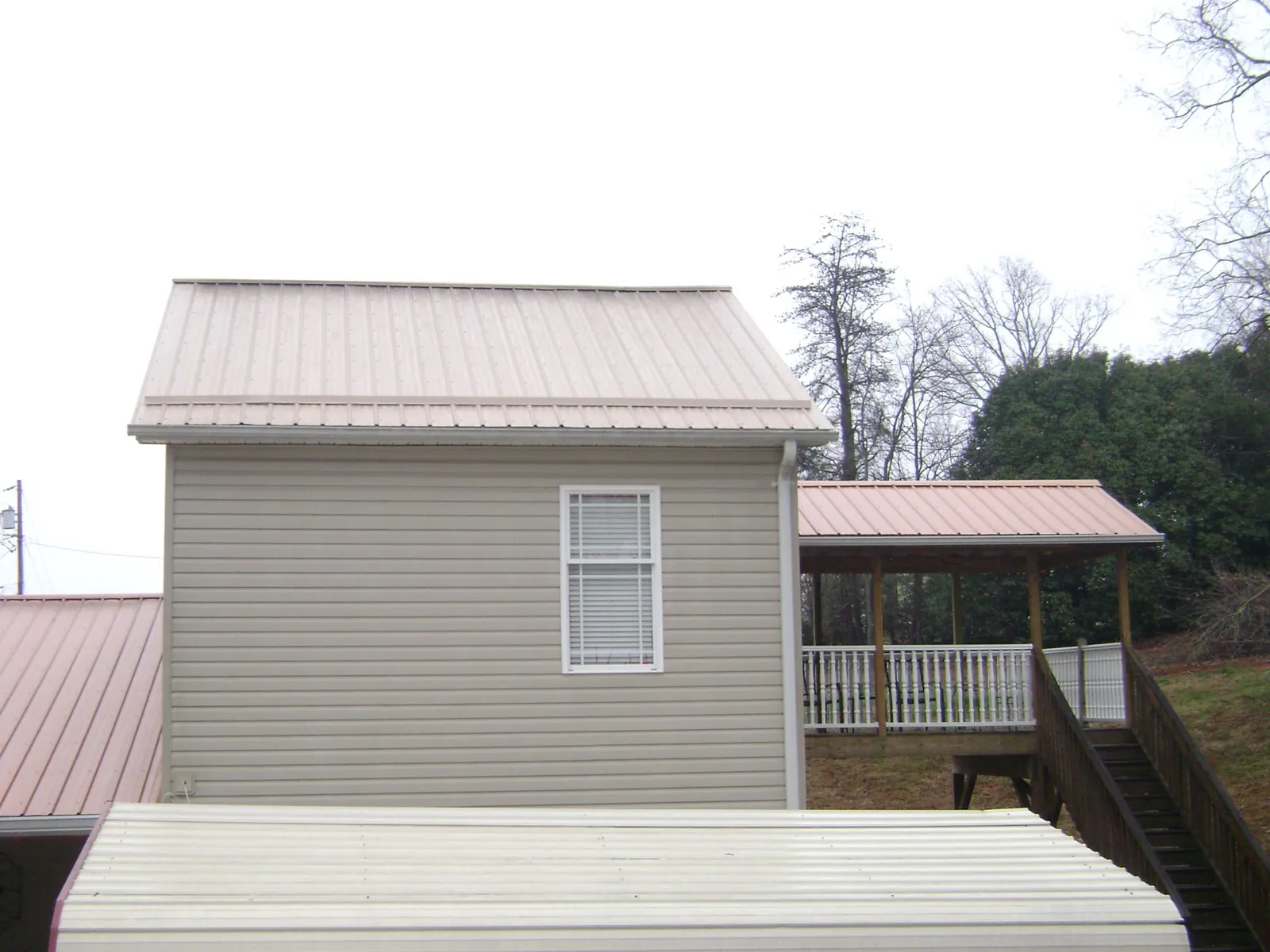 Tan metal roofs on a two story addition and attached porch, from a Roof Replacement job in Sully