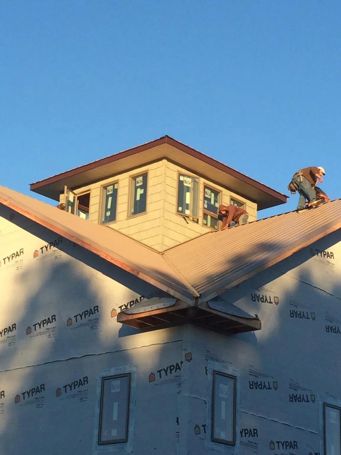 Roofers working around a rooftop cupola on a new metal roof at sunset — Roof Waterproofing in Sully by Roofing Brothers